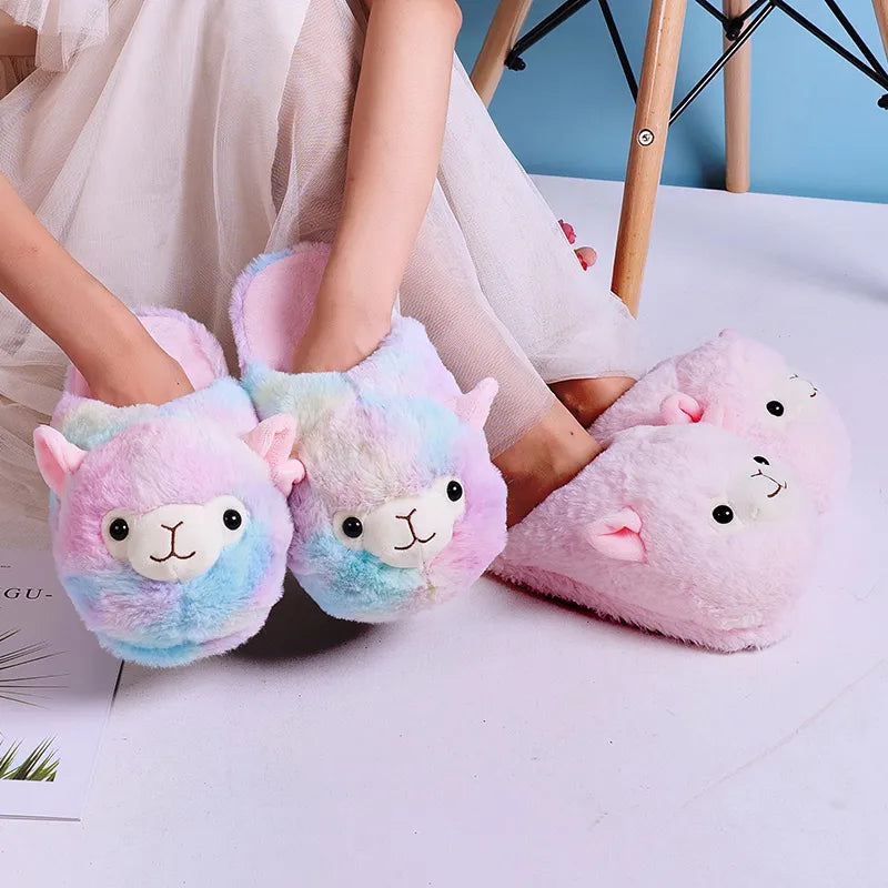 Person sitting on the floor wearing pink alpaca slippers on their feet, holding up rainbow-colored alpaca slippers in their hands.